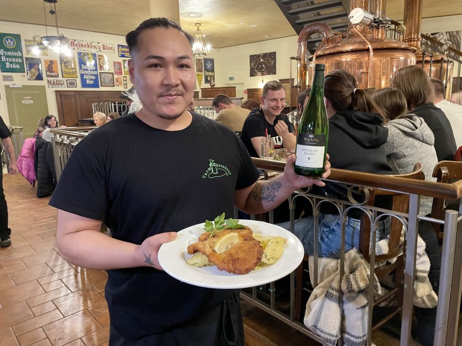 <who>Photo credit: Steve MacNaull/NowMedia Group</who>Arash brings over the signature brauhaus pork schnitzel with Rolf Willy Mit Rivaner Riesling at Turm-Brauhaus restaurant in Chemnitz.